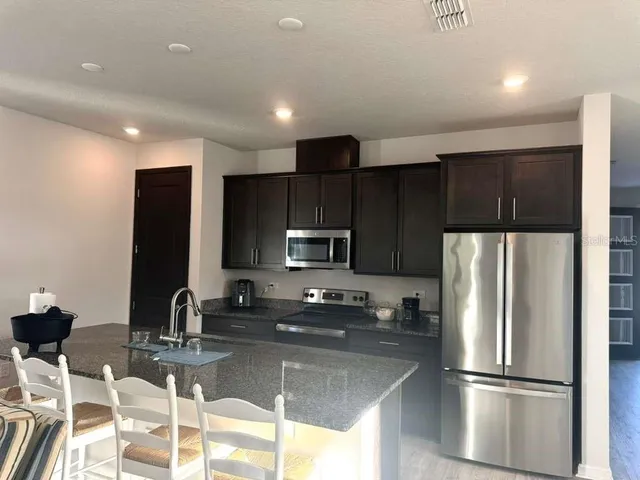 a kitchen with stainless steel appliances wooden cabinets a refrigerator and a sink