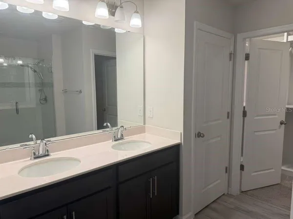 a bathroom with a double vanity sink mirror and shower