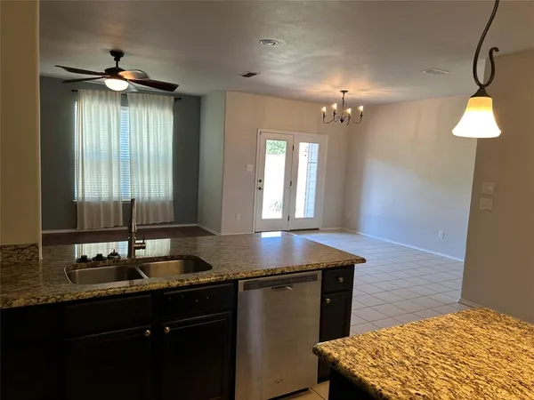 an empty room with kitchen view and natural light