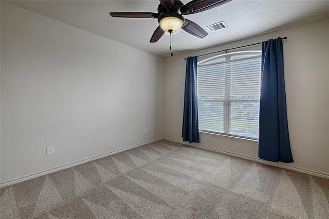 a view of an empty room with window and a kitchen