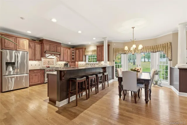 a kitchen with stainless steel appliances granite countertop a refrigerator a stove top oven a sink dishwasher a dining table and chairs with wooden floor