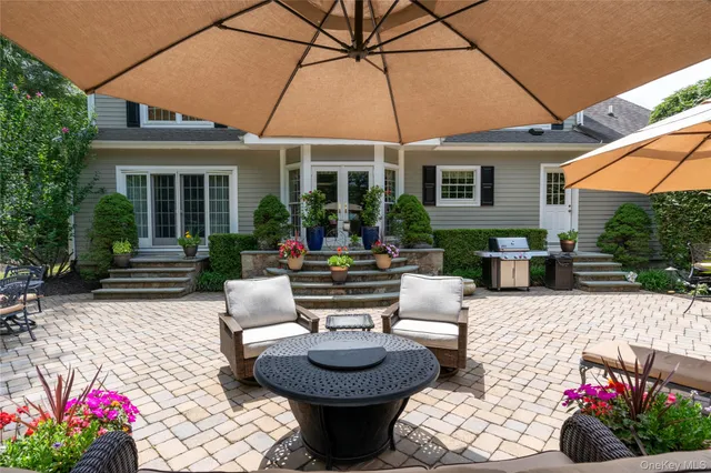 a view of a patio with couches table and chairs under an umbrella