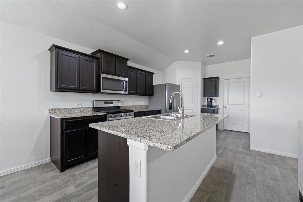 4600 Fringetree Way Crowley, TX 76036 - Photo 9 of 40 Kitchen island featuring a double basin sink and a high-arc faucet, complemented by granite countertops