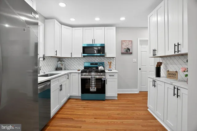a kitchen with stainless steel appliances granite countertop a stove top oven a sink and white cabinets