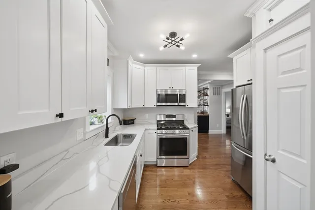 a kitchen with white cabinets and sink