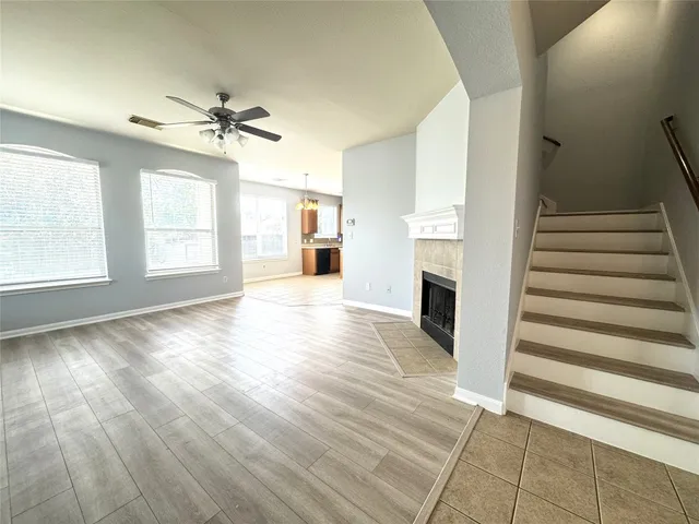 a view of an empty room with wooden floor fireplace and a window
