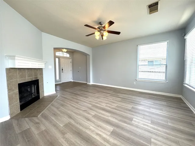a view of an empty room with window and wooden floor