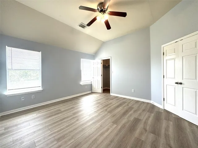 a view of empty room with wooden floor and fan