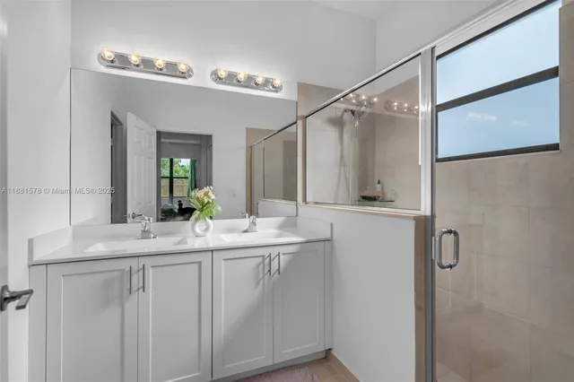 a bathroom with a double vanity sink mirror and shower