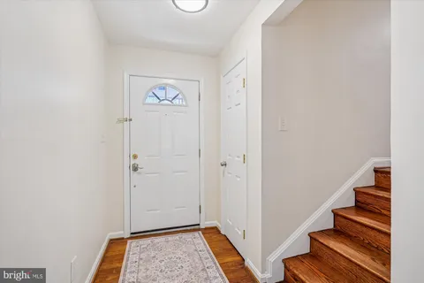 a view of an empty room with wooden floor fireplace and a window