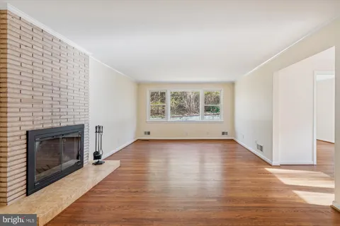 a view of an empty room with wooden floor and a fireplace
