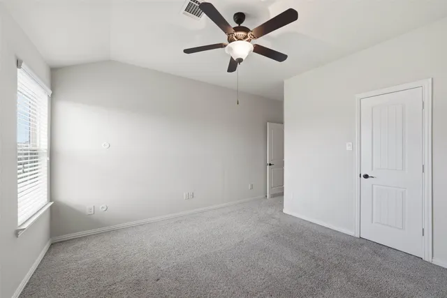 an empty room with a ceiling fan and window