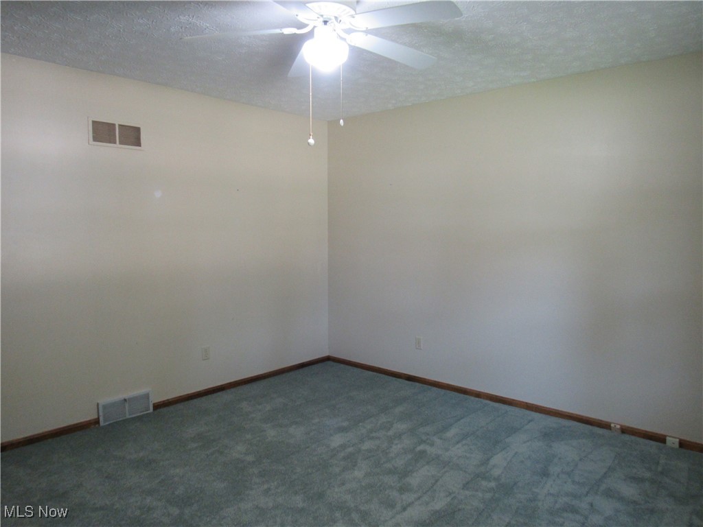 1120 Vincent Road Southeast North Canton, OH 44720 - Photo 41 of 50 Front bedroom new carpet with ceiling fan and a textured ceiling