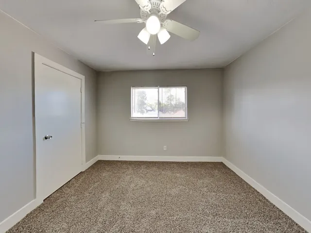 an empty room with a chandelier fan and windows