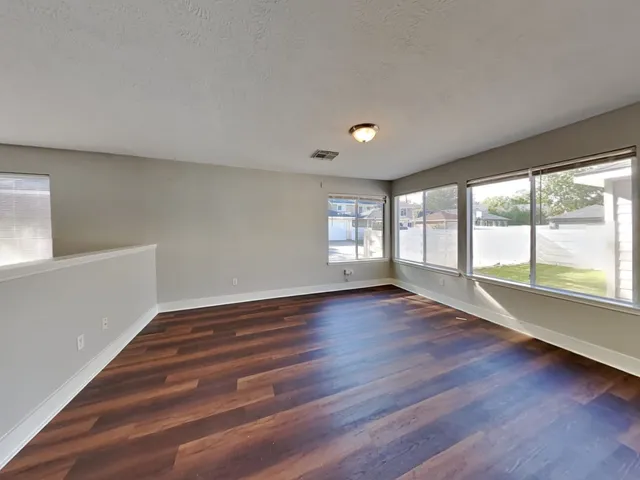 a view of an empty room with wooden floor and a window
