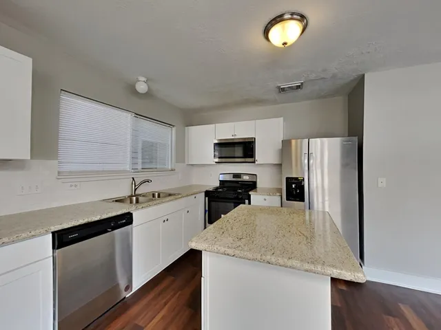 a kitchen with a sink a microwave a refrigerator and cabinets