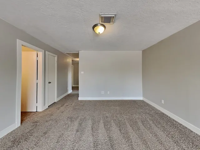 a view of an empty room and kitchen view