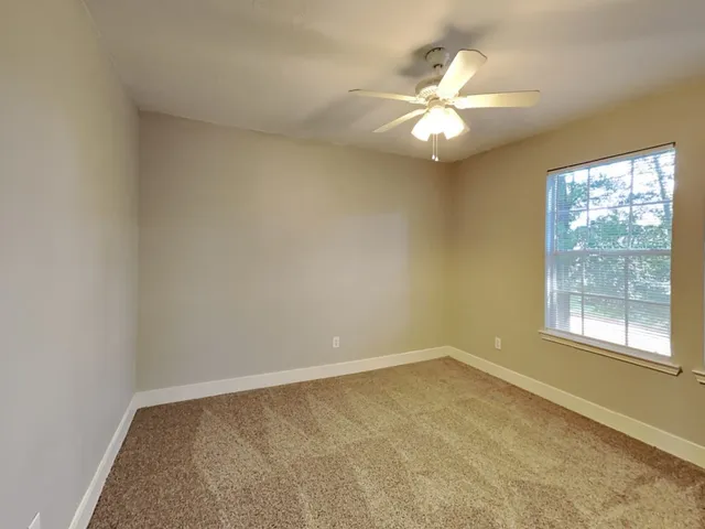 an empty room with a window and a fan