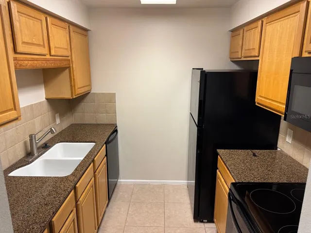 a kitchen with a granite countertop sink stove and refrigerator