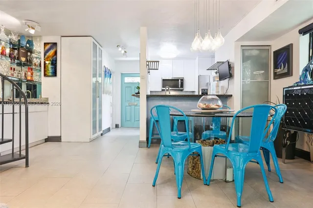 a kitchen with stainless steel appliances kitchen island granite countertop a refrigerator and a dining table