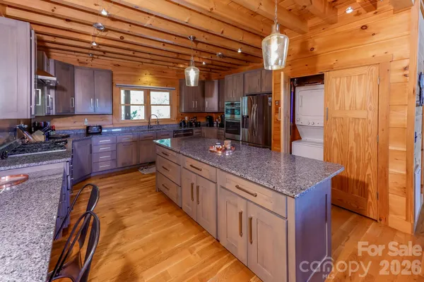 a large kitchen with kitchen island granite countertop a sink and wooden cabinets