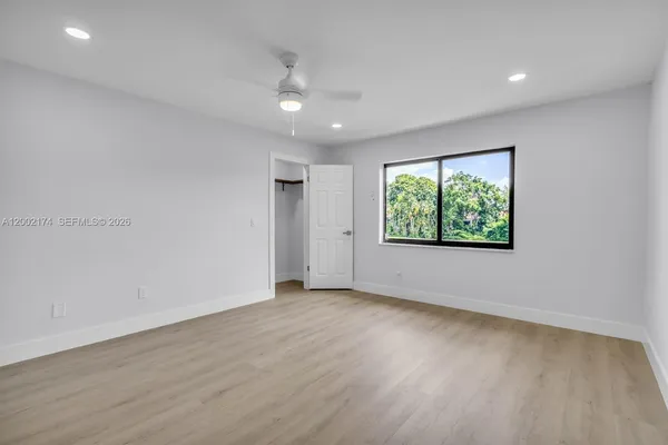 an empty room with wooden floor and windows