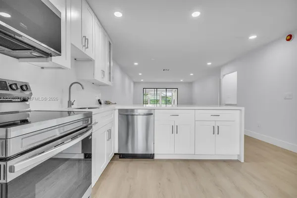 a view of kitchen with stainless steel appliances granite countertop a stove and a sink