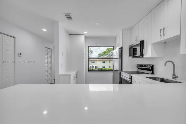 a kitchen with stainless steel appliances a sink a stove a refrigerator a counter top space and cabinets