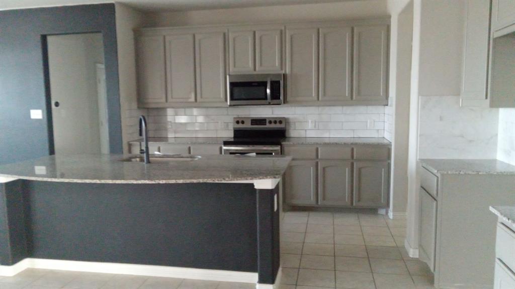 128 Spring Creek Circle Paradise, TX 76073 - Photo 7 of 21 a kitchen with stainless steel appliances granite countertop a sink a stove a microwave and a refrigerator