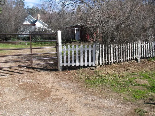 a view of a yard with wooden fence