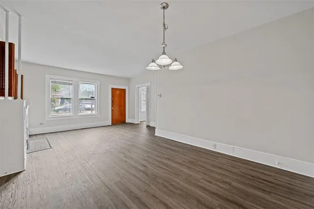 an empty room with wooden floor cabinet and windows