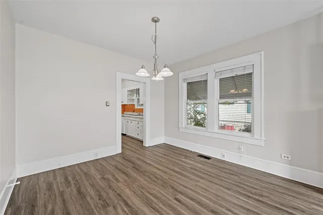 a view of an empty room with window and wooden floor