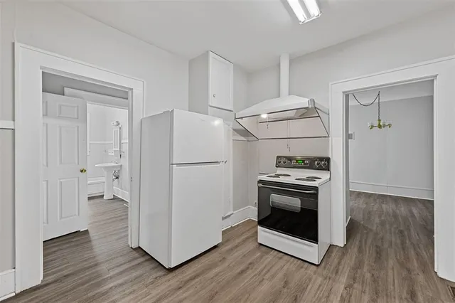 a kitchen with a stove a refrigerator and a hard wood floor