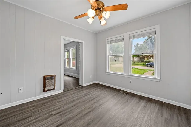 a view of an empty room with window and wooden floor
