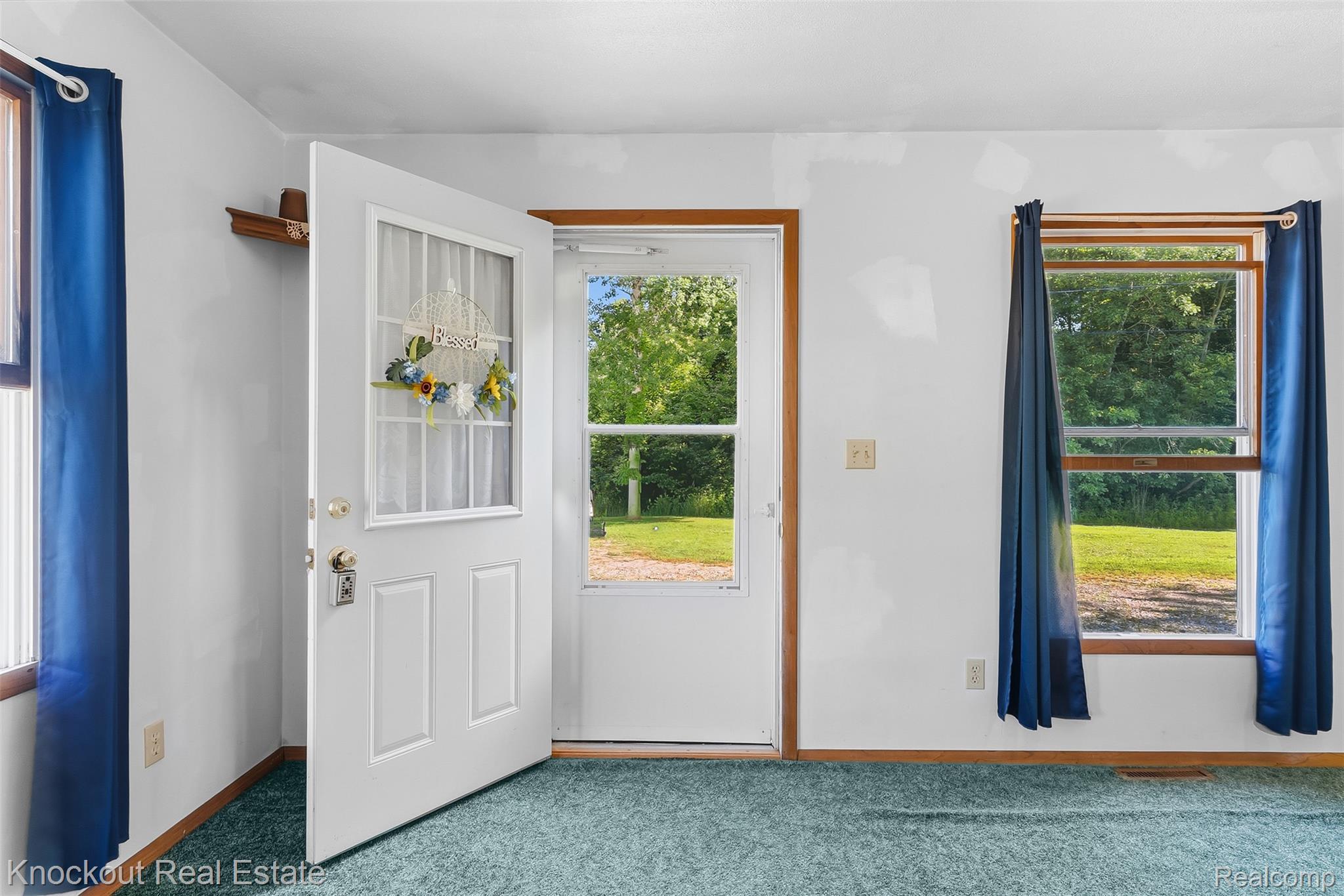 12845 Bueche Road Burt, MI 48417 - Photo 4 of 28 Entryway featuring a white paneled door with decorative glass, wood-framed windows, and turquoise carpeting