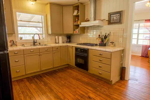 a kitchen with stainless steel appliances granite countertop a sink cabinets and wooden floor