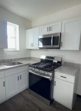 a kitchen with granite countertop white cabinets and stainless steel appliances