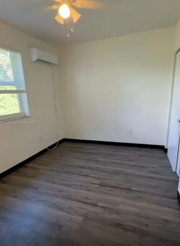 a view of an empty room and wooden floor and a window