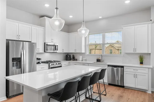 a kitchen with appliances a sink a center island and cabinets