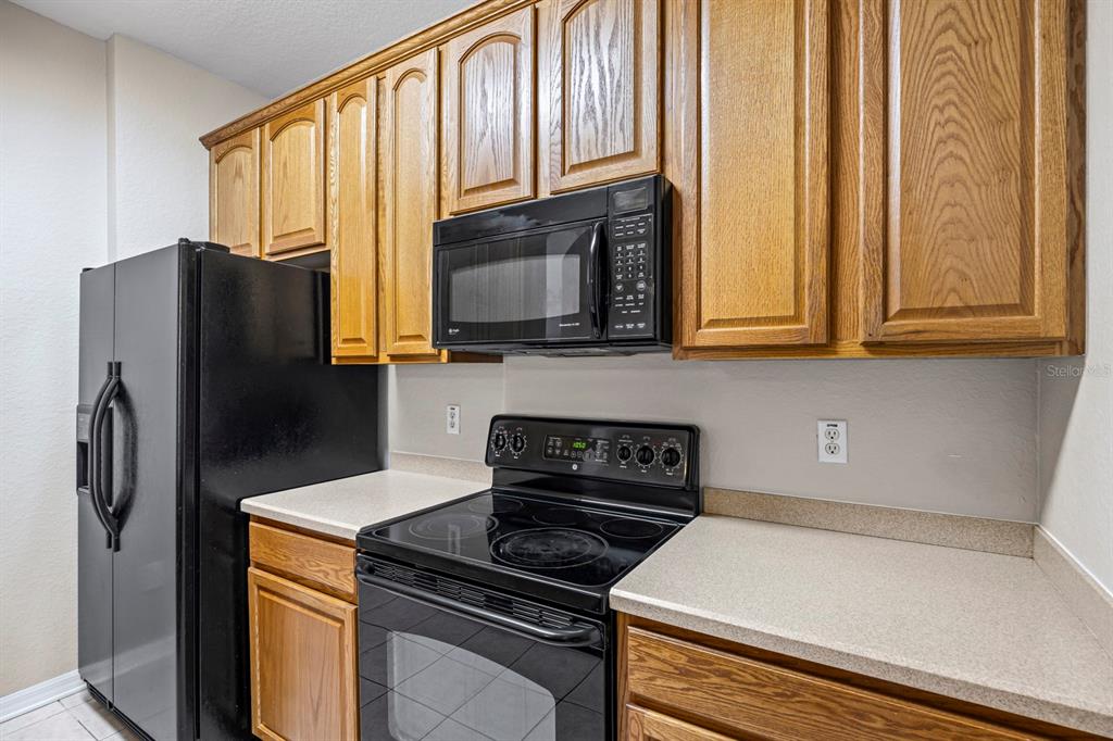 1355 Venezia Court, Unit 405 Davenport, FL 33896 - Photo 6 of 30 a kitchen with stainless steel appliances granite countertop a refrigerator stove and microwave