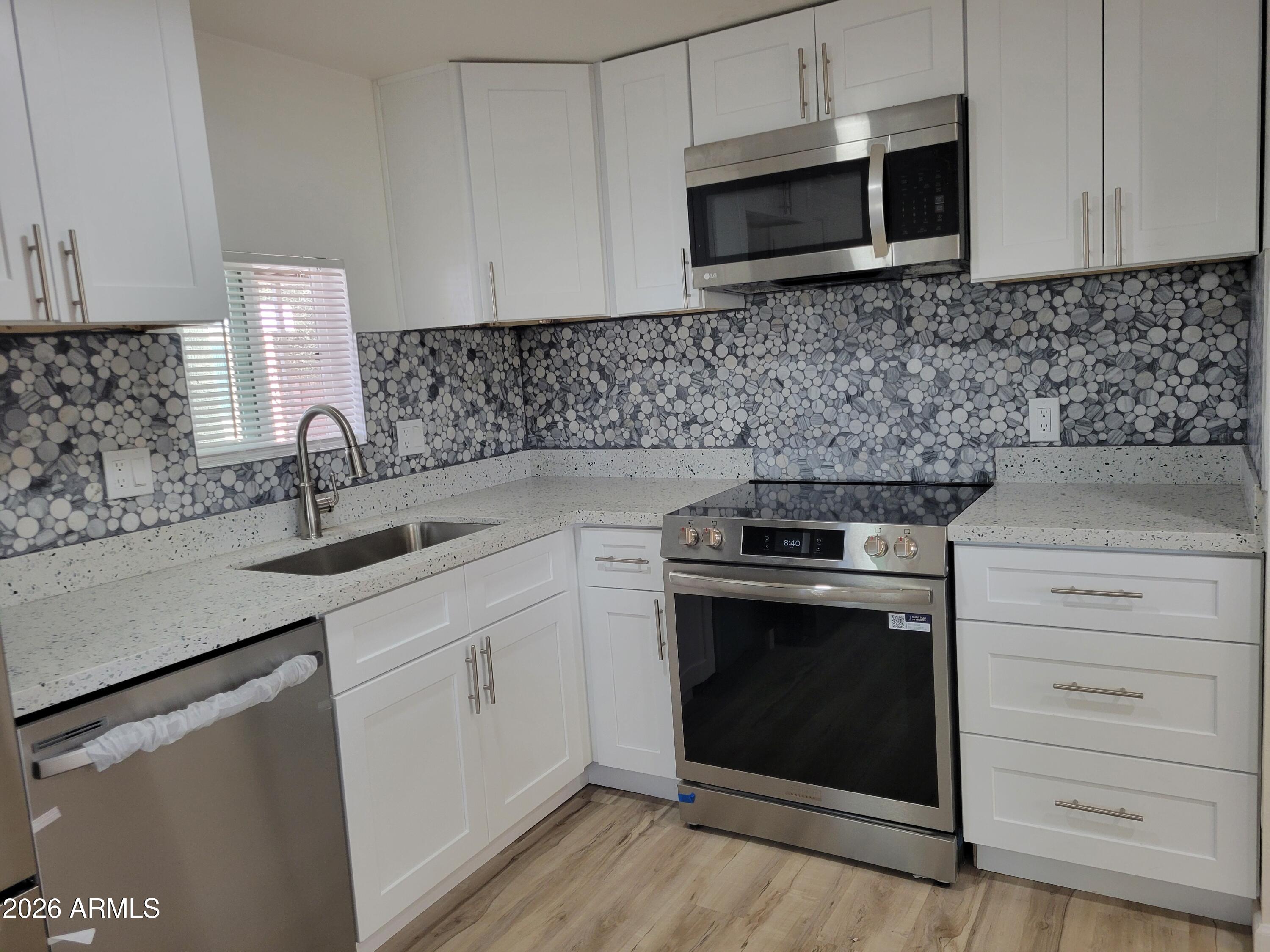 18026 North Cave Creek Road, Unit 1 Phoenix, AZ 85032 - Photo 4 of 14 a kitchen with stainless steel appliances granite countertop a sink stove and microwave