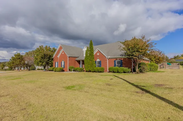 a front view of house with yard and trees in the background
