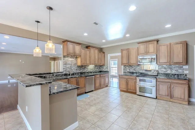 a kitchen with kitchen island granite countertop a stove a sink a center island a stove and cabinets