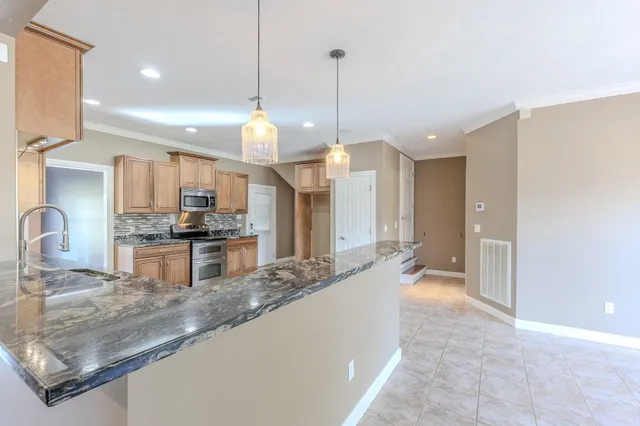 a large kitchen with kitchen island a large counter top a sink stainless steel appliances and cabinets
