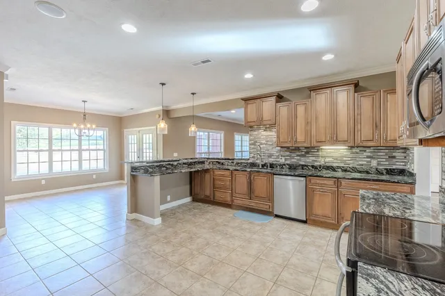 a large kitchen with kitchen island granite countertop a stove a sink a dining table and chairs