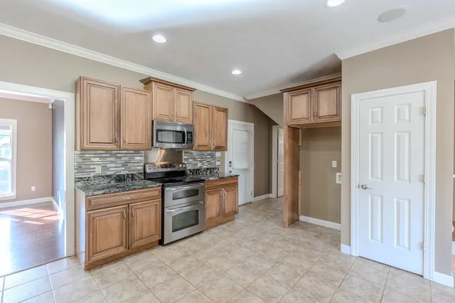 a large kitchen with stainless steel appliances granite countertop a stove and a sink