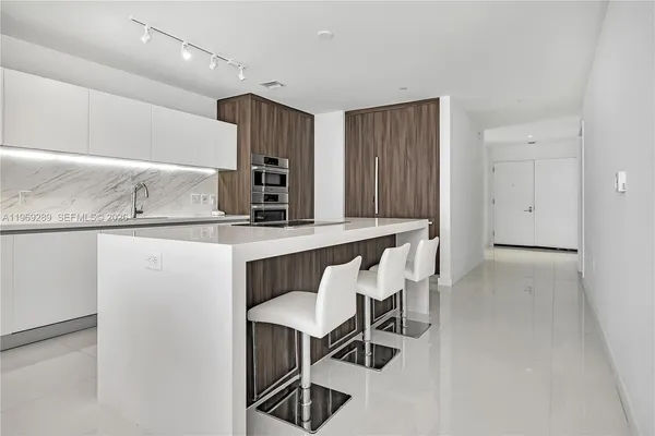 a kitchen with stainless steel appliances kitchen island a table chairs in it and wooden floors
