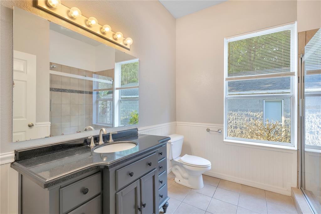 704 Grape Avenue St. Cloud, FL 34769 - Photo 10 of 30 a bathroom with a granite countertop sink toilet a large mirror and a window