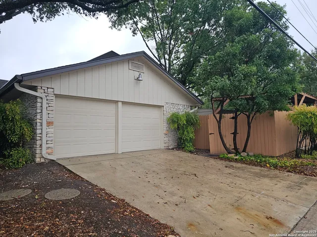 a view of a house with a small yard plants and a large tree