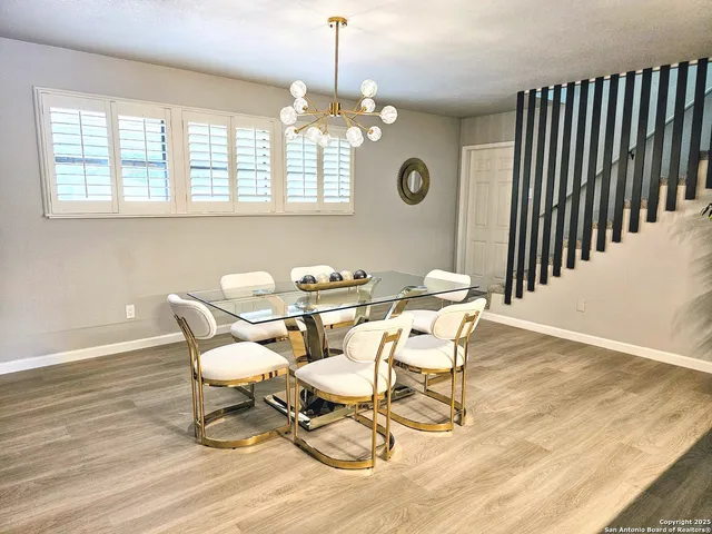 a dining room with wooden floor a chandelier a glass table and chairs